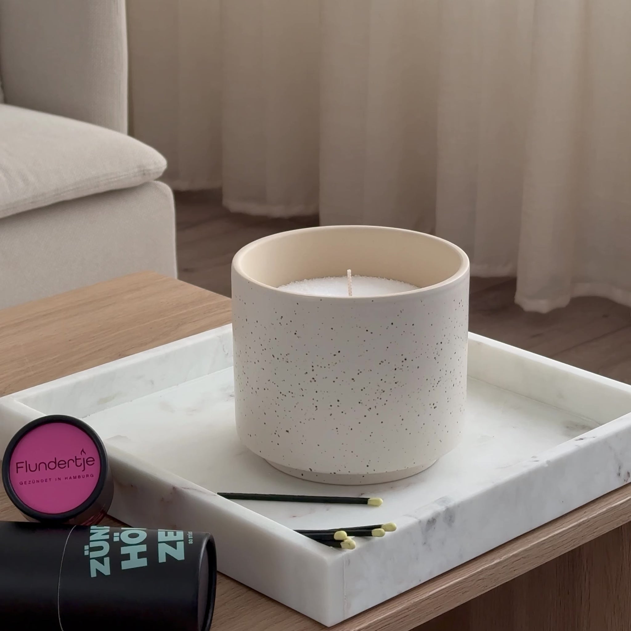 farbige Streichhölzer zünden eine Kerze in einem Wohnzimmer an